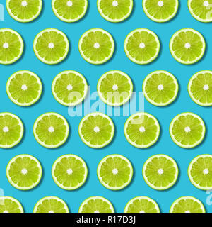 Green lime slices pattern on vibrant turquoise color background. Minimal flat lay food texture Stock Photo