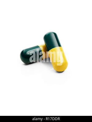 Two dark green and yellow medication pill capsules, still life