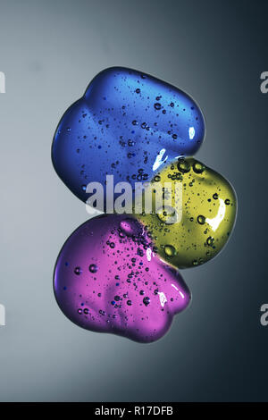 Three blobs of gel, blue, purple and green on grey background Stock Photo