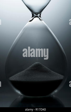 Traditional hourglass egg timer with grains of sand in bottom half showing the end of time, studio shot, close up detail Stock Photo