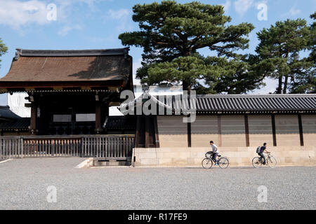 Cyclists outside the gates of the imperial palace in Kyoto, Japan Stock Photo