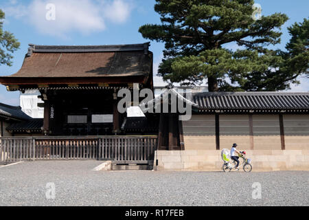 Cyclists outside the gates of the imperial palace in Kyoto, Japan Stock Photo