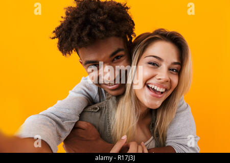image of happy cute young loving couple posing isolated over yellow background hugging take a selfie by camera r17j3j