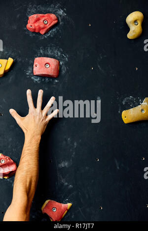 Macro shot of climbers hands gripping colourful handholds during indoor workout Stock Photo
