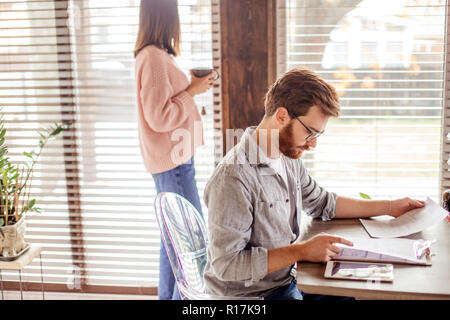 Young european man reading documents while sitting at table at home Stock Photo