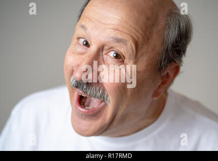 Smiling and laughing 60s year old senior man candid close up portrait in human emotions and facial expressions concept isolated in neutral background. Stock Photo