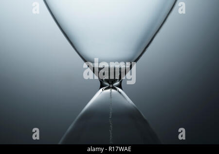 Close up view of white sand trickling through contemporary hourglass, plain background Stock Photo