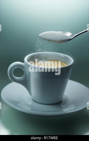 Pouring sugar from teaspoon into cup of coffee, plain background Stock Photo