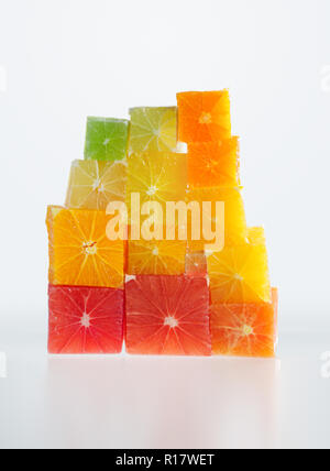 Pile of colorful cubed citrus fruit, white background Stock Photo