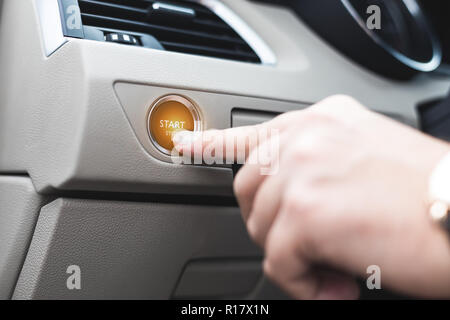 Car start stop system with finger pressing the button, horizontal image Stock Photo