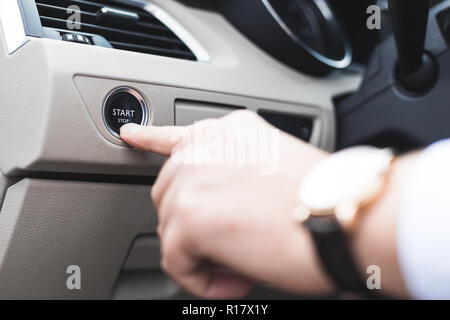 Car start stop system with finger pressing the button, horizontal image Stock Photo