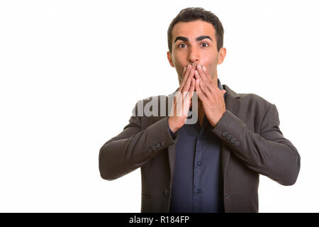 Portrait of young handsome Persian businessman looking surprised Stock Photo