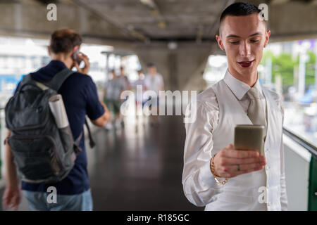 Young androgynous homosexual LGTB businessman using phone Stock Photo