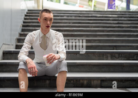 Young androgynous homosexual LGTB businessman sitting on stairs Stock Photo