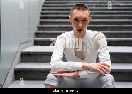 Young androgynous homosexual LGTB businessman sitting on stairs Stock Photo
