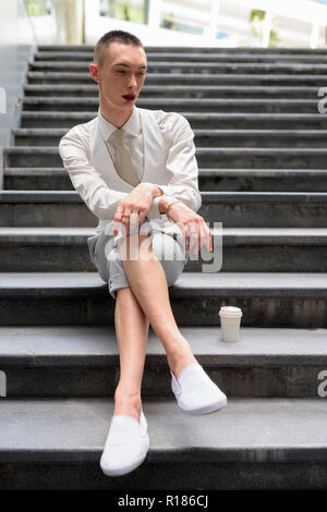 Young androgynous homosexual LGTB businessman sitting on stairs Stock Photo