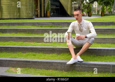 LGTB businessman sitting on stairs while using laptop computer Stock Photo