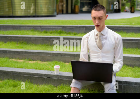 LGTB businessman sitting on stairs while using laptop computer Stock Photo