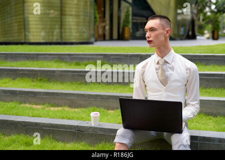 LGTB businessman sitting on stairs while using laptop computer Stock Photo