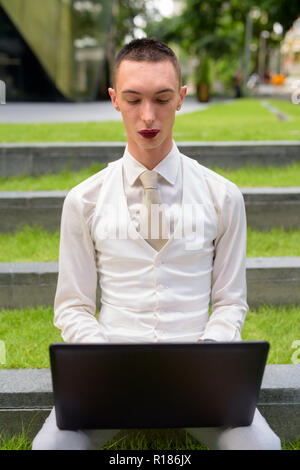 LGTB businessman sitting on stairs while using laptop computer Stock Photo
