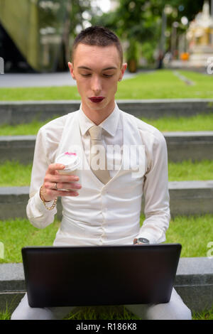 LGTB businessman sitting on stairs while using laptop computer Stock Photo