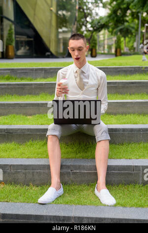LGTB businessman sitting on stairs while using laptop computer Stock Photo
