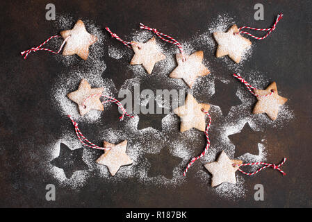 Christmas star shaped gingerbread cookies with red ropes and golden balls for Christmas tree decoration on rustic background, top view. Stock Photo