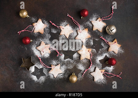 Christmas star shaped shortbread cookies with red ropes for Christmas tree decoration on dark rustic background, top view. Stock Photo