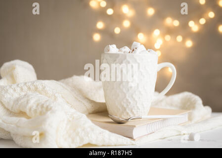 Christmas Hot chocolate with marshmallows in white mug, copy space. Hot cocoa drink for Christmas and winter holidays with warm scarf, lights, festive Stock Photo