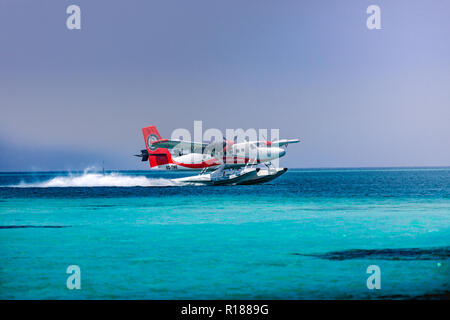 Red and white seaplane approaching island in the Maldives. Transmaldivian airlines in Maldives island Stock Photo