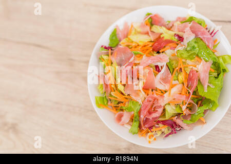 Arugula, prosciutto, mozzarella salad and melon on a white dish on a wooden table, top view Stock Photo