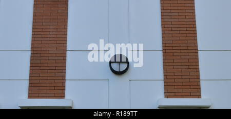 beautiful outside wall of a building with a lamp in the middle between two brick columns Stock Photo