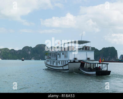 Junk boat tourist cruise of emerald water of Halong Bay South China Sea Vietnam Asia with limestone island peaks covered in jungle foliage Stock Photo