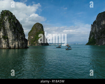 Fishing boats and tourist junk cruise boats in Halong Bay South China Sea Vietnam Asia cruising around spectacular limestone island peaks covered in p Stock Photo
