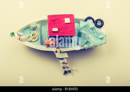 Tiny wrapped figurine of man model beside a model boat Stock Photo