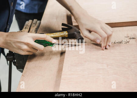 Thai engineer student prying nail from a wooden prank in carpentry workshop class. Stock Photo