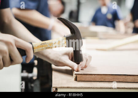 Thai Engineering Student hit a nail using hammer in engineering workshop class Stock Photo