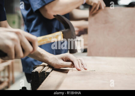 Thai Engineering Student hit a nail using hammer in engineering workshop class Stock Photo
