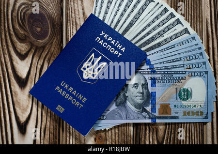 A bundle of banknotes of 100 dollars in a biometric blue foreign passport of a citizen of Ukraine Stock Photo
