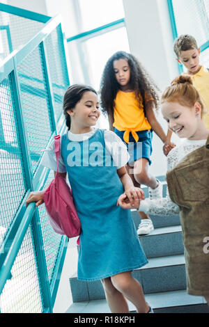 happy adorable classmates walking down stairs at school Stock Photo