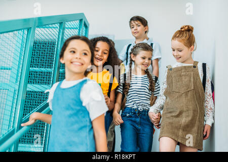 group of happy classmates walking down stairs at school Stock Photo