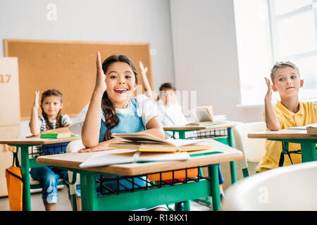 group of pupils raising hands to answer question during lesson Stock Photo
