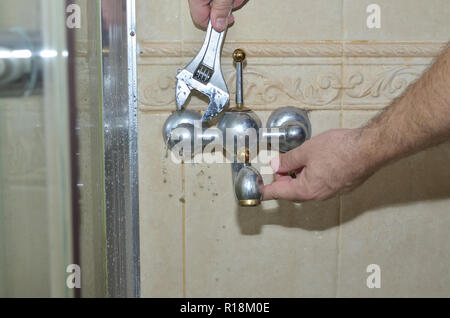 Man's hands with a plumber wrench starting to remove an old bathroom faucet Stock Photo