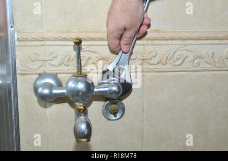 Unscrewing an old bathroom faucet with a wrench Stock Photo