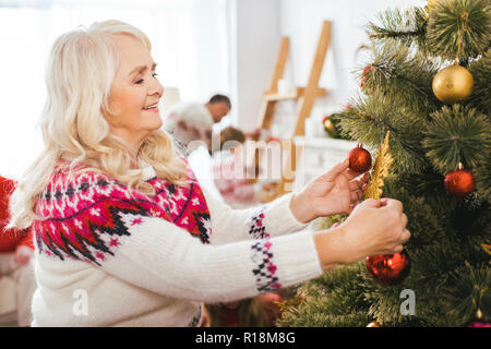 happy senior woman decorating christmas tree Stock Photo