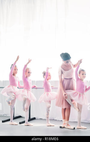 young woman teaching adorable kids dancing in ballet school Stock Photo