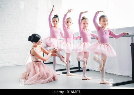 young woman teaching adorable children dancing in ballet school Stock Photo