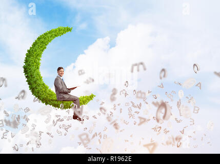 Man or student sitting on green moon and reading book Stock Photo