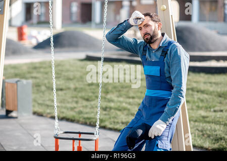 Portrait of a tired workman in uniform on the playground outdoors Stock Photo