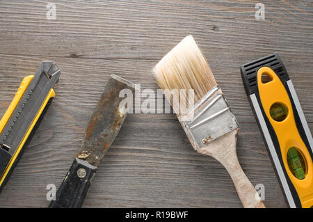 Knife, Spatula, Paint Brush and Level on Wooden Background Stock Photo